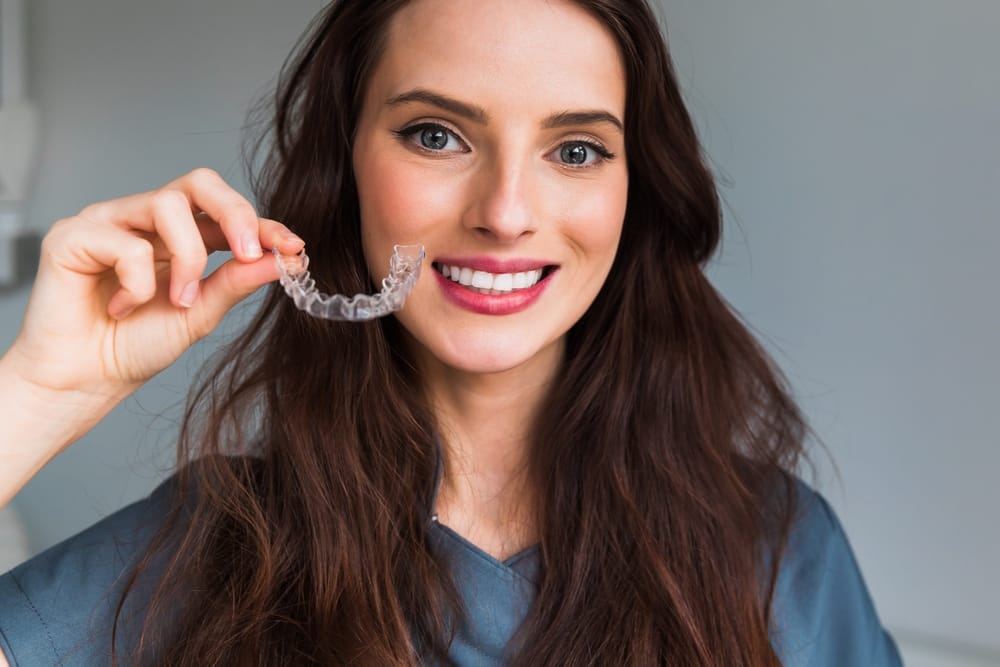 Young beautiful woman holding dental aligner orthodontic - Invisalign 